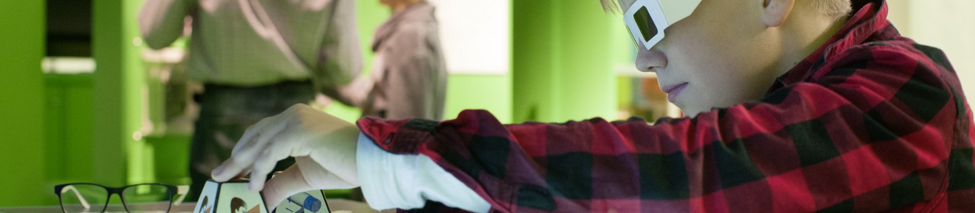 Ein Junge mit einer 3D-Brille verschiebt Objekte auf einem Medientisch.